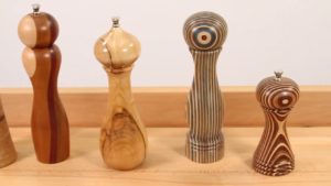 A group of turned peppermills on a work bench.