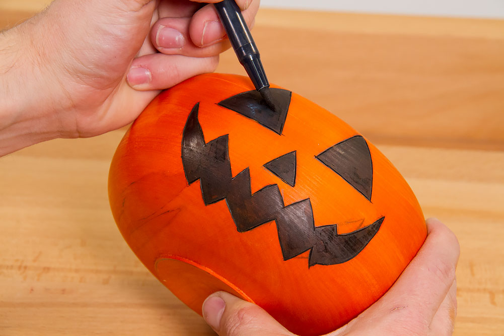 Coloring the pumpkin face details with a black marker.