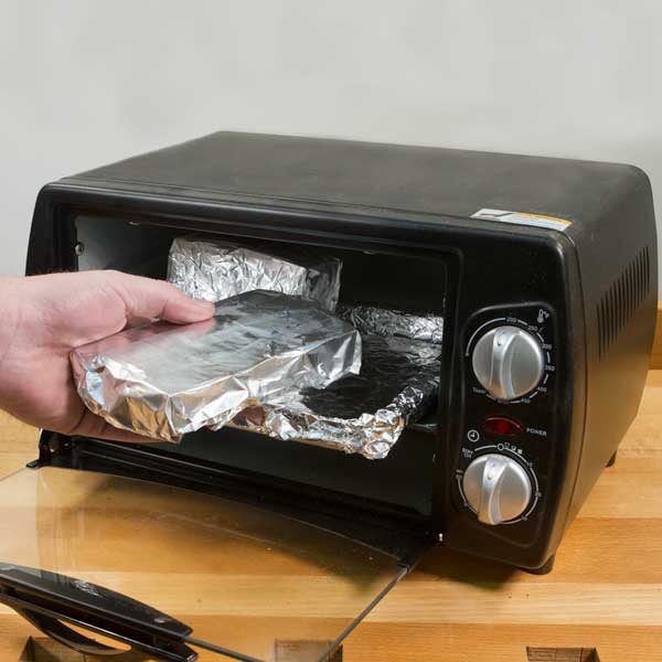 Placing tin foil wrapped blanks into a toaster oven.