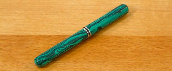 A closed end pen laying on a table.