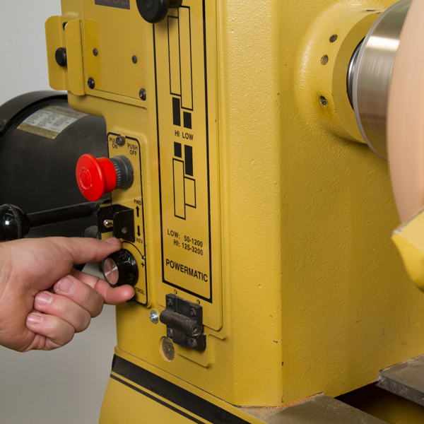 Adjusting the speed dial on a lathe.