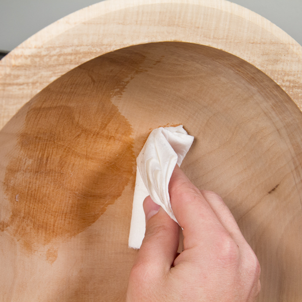 Rubbing paste wax into the wood with a paper towel.