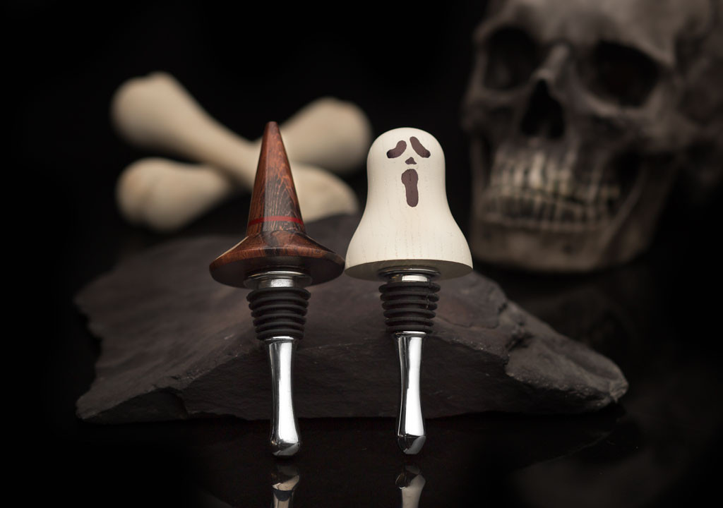 A witches hat and ghost bottle stopper on a spooky background.