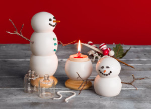 A couple of confetti light snowman with a lit candle flame.