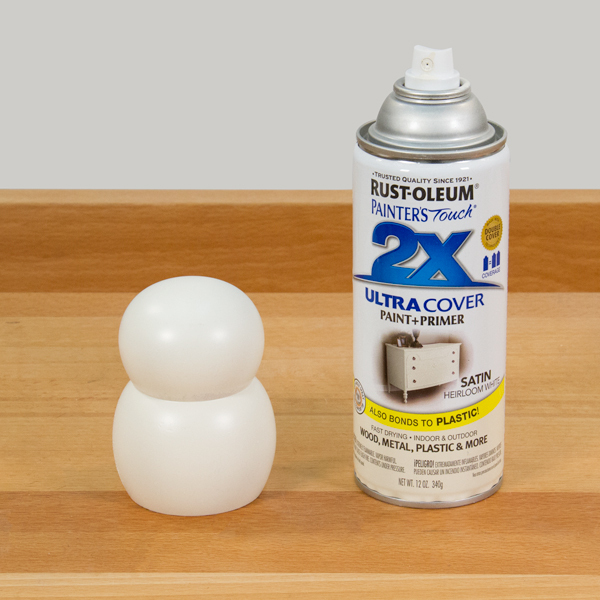 A can of white spray paint and a freshly painted snowman body.