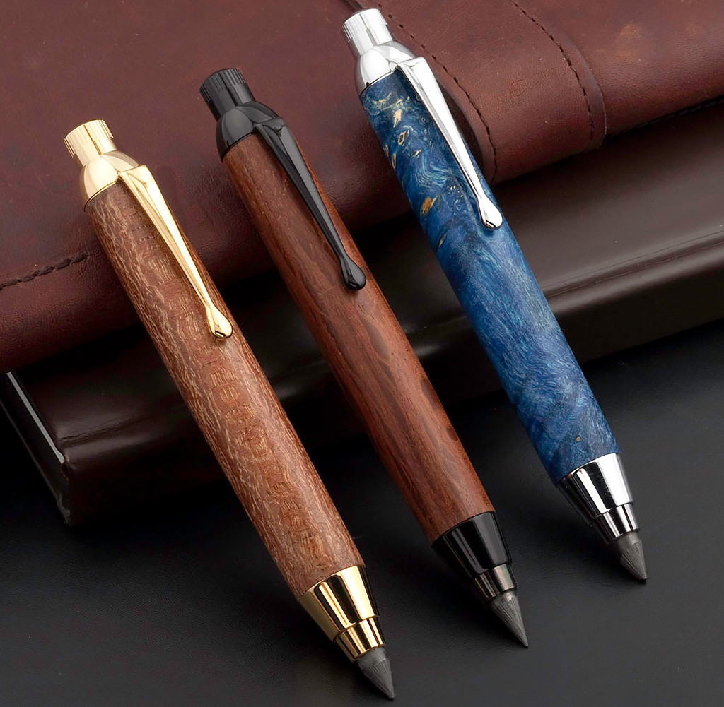 Three turned sketch pencils laying on a leather notebook.
