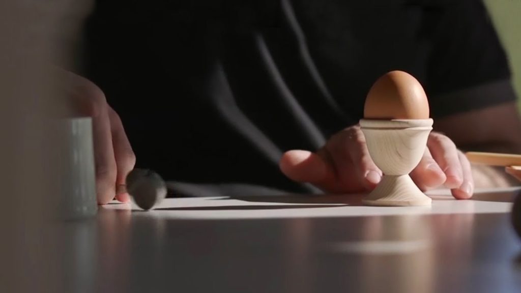 An egg sitting in an egg cup on a kitchen counter.