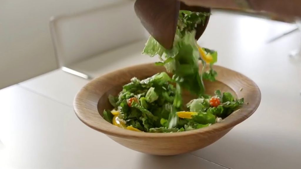 Adding salad to a turned bowl.