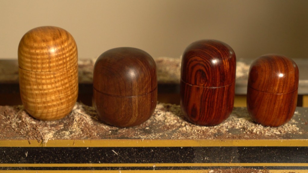 A set of four capsule boxes arranged on a lathe bed.
