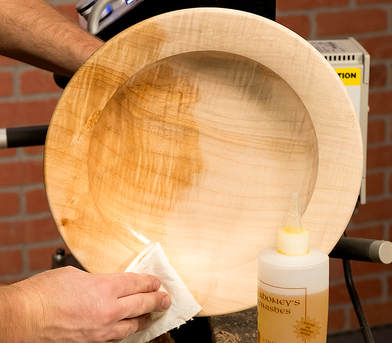 Applying walnut oil finish to the platter interior with a paper towel.