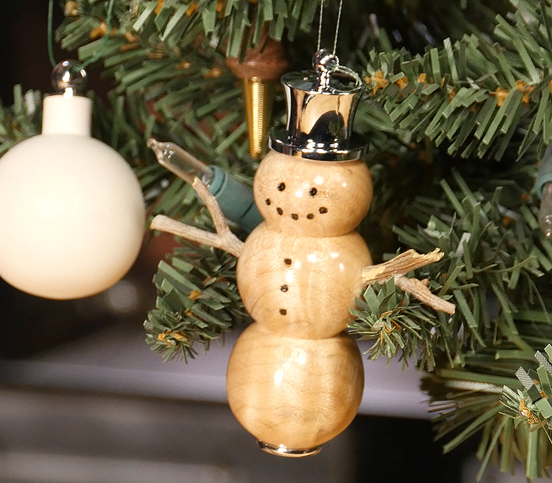 The finished snowman ornament hanging on a Christmas tree.