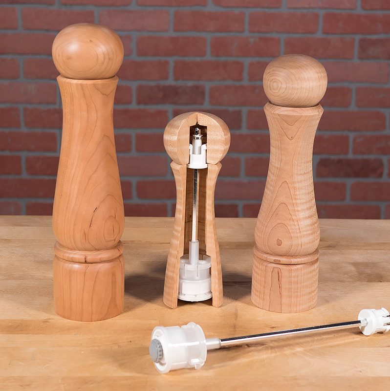 A set of Crushgrind mills on a table with one cut in half to show mechanism.